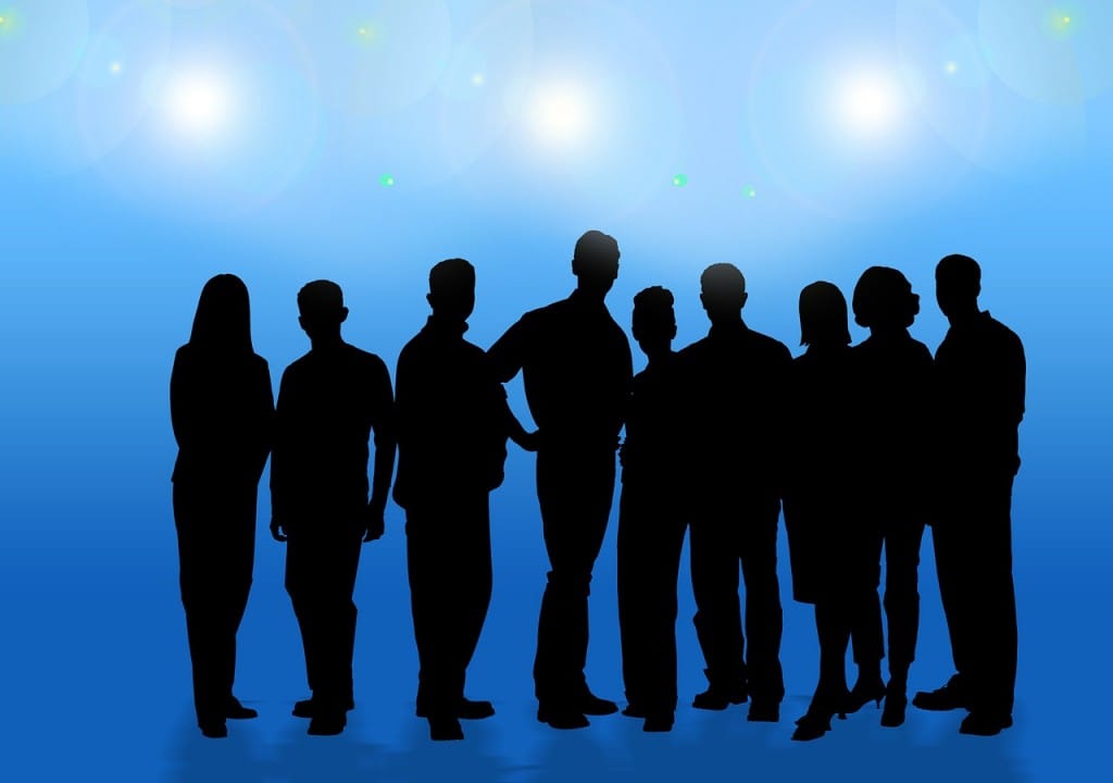 青い背景にスポットライトを浴びるビジネスチームのシルエット